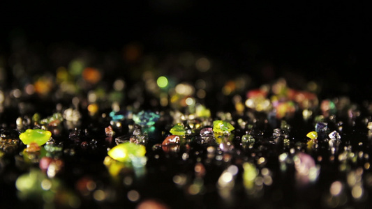 黑桌子上散落的钻石形彩色晶体泛射视频
