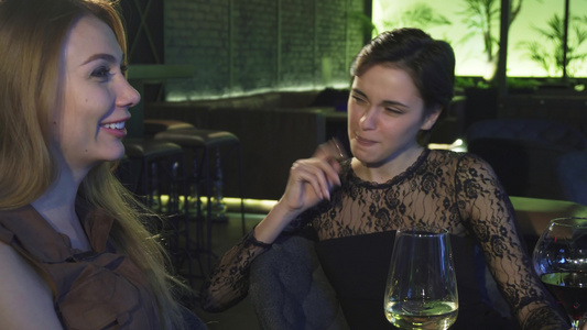 两个美丽的快乐女孩笑着在酒吧里聊天喝着饮料视频