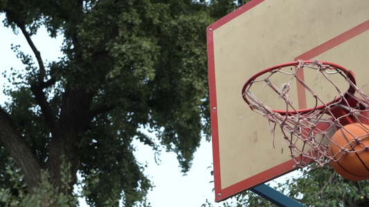 橙色篮球在公园的街头法庭上打篮子击中目标达到目标视频