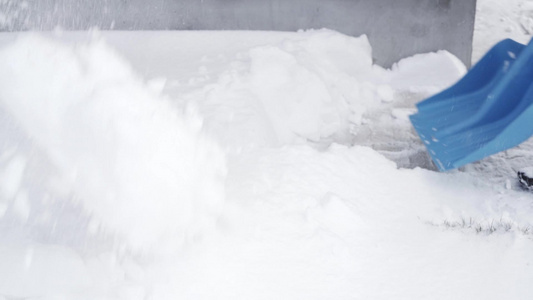 用蓝色的铲子缓慢移动地把房子周围的雪拿起视频