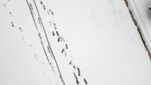 空中无人驾驶飞机在积雪上看到脚印和滑雪足迹16秒视频