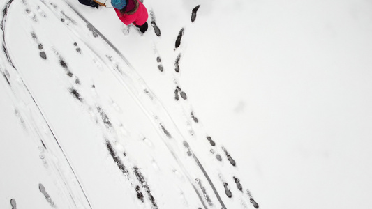 母亲在新鲜的雪地上用雪橇拉着孩子从上面可见的脚印女人视频