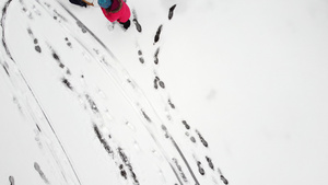 母亲在新鲜的雪地上用雪橇拉着孩子从上面可见的脚印女人9秒视频