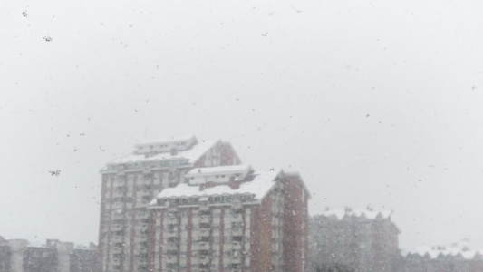 城市中缓慢运动的雪花落下背景中的建筑视频