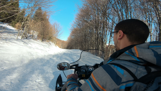 在阳光明媚的一天男子驾驶运动车在森林里骑雪地运动视频
