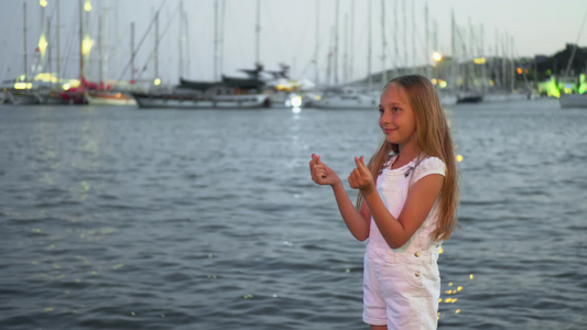 十几岁的女孩在晚上海港景观上随风飘扬的头发快乐的女孩视频