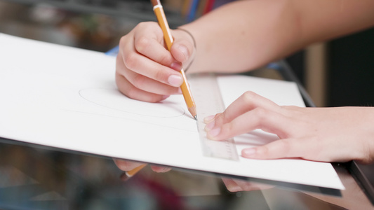 年轻女孩用标尺和铅笔在一张白纸上画一条线视频