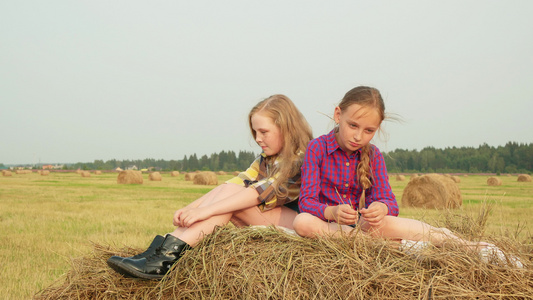 十几岁的女孩坐在高峰干草堆上严肃的女孩少年在收割场视频