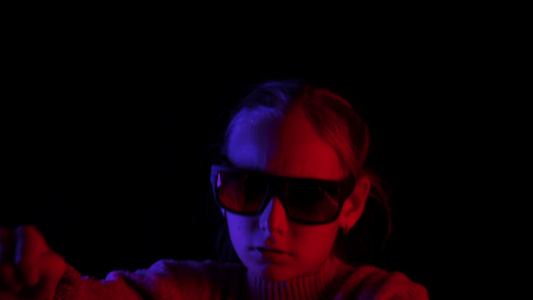 戴着深色太阳镜的少女在黑色背景上用蓝色和红色的灯光视频