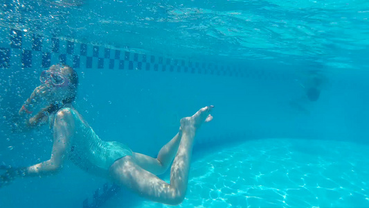 戴着眼镜和泳装的少女在水下游泳池游泳水下护目镜的女孩视频