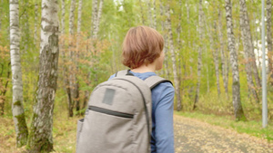 十几岁的男孩背着背包走在秋天公园的小路上秋季假期在26秒视频