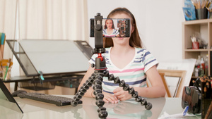 智能手机在三脚架上拍摄一个年轻女孩说话16秒视频