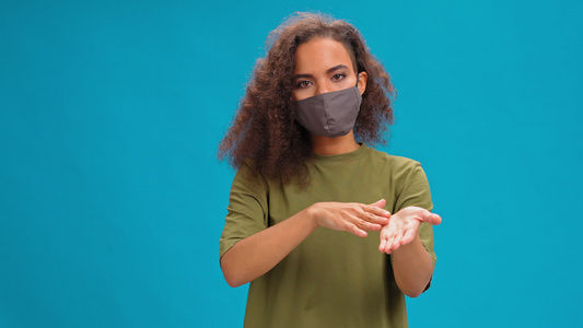 身戴保护面罩的年轻女子看着镜头穿着橄榄T恤衫在蓝背景视频