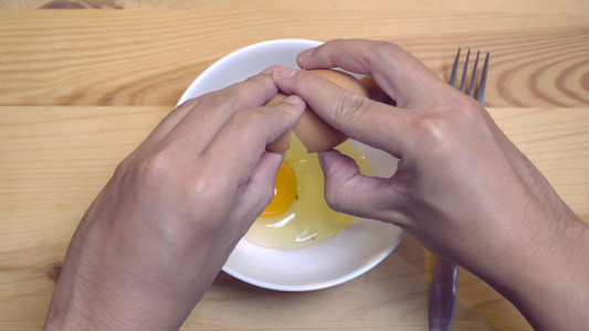 手握紧在白碗里打鸡蛋早上准备煎蛋卷做早餐视频