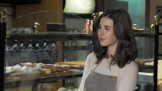 迷人的女面包师在面包店对照相机微笑视频