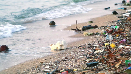 沙滩上留下塑料橡胶和废物海面日落海浪将它们吹入海中视频
