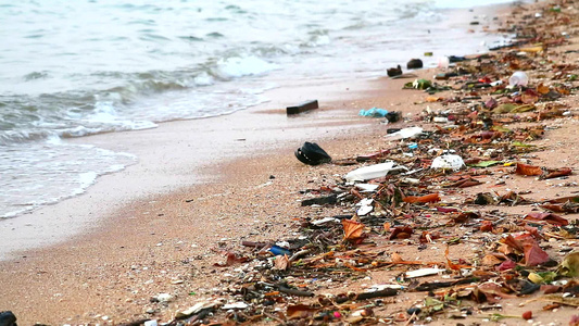 沙滩上留下塑料橡胶和废物海边日落海浪将它们吹入海中视频