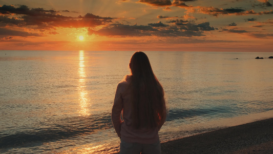女人用伸展的手臂享受海中日落的美景视频