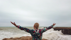女孩举起手来在暴风雨中与她一起站在海岸上6秒视频