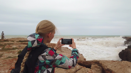 女孩站在她的背上在她的手机上拍张照片在海中视频