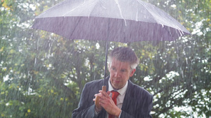 商人躲在雨伞下躲避雨雨下的雨伞下17秒视频