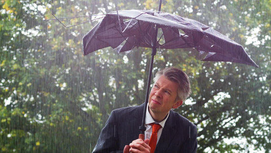 在雨中躲在破碎的雨伞下被遮盖着的商人视频