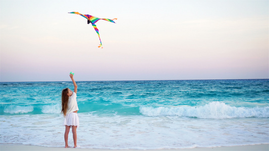 日落时在热带海滩放风筝的小女孩孩子在海边玩耍有沙滩视频