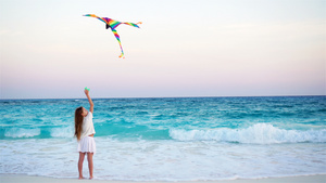 日落时在热带海滩放风筝的小女孩13秒视频
