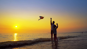 一个小男孩和父亲玩游戏在日落暑假的概念下发起风筝23秒视频
