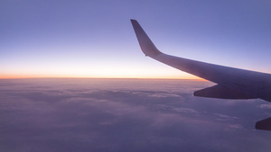 日落时从飞机窗处的视线在云上方飞过10秒视频