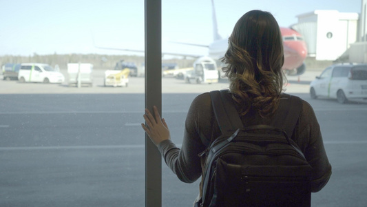 机场的年轻旅游女青年在飞机上透过窗户看一看视频