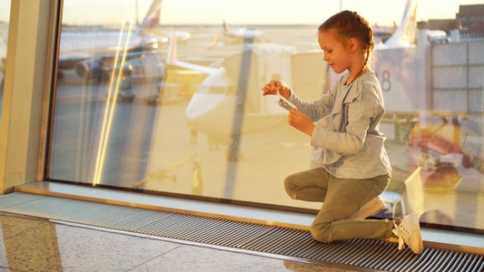 可爱的小女孩在机场等待登机时玩小模型飞机飞行和飞机视频