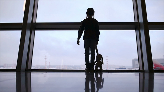 在机场靠近大窗户的小女孩在等待登机时等候登机视频