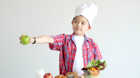 男孩拿着苹果站在包括蔬菜在内的有机食品的前面站着视频