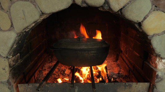 在明火的烤箱中烹饪食物与食物的铸铁大锅木柴和烤箱里视频