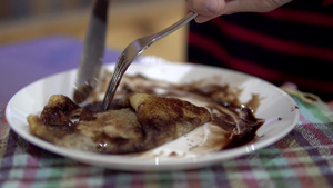 男孩吃煎饼饼干加混合装满香蕉和在餐厅的盘子里的巧克力18秒视频