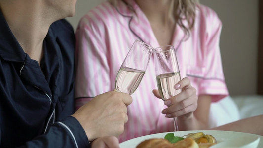 年轻夫妇开瓶香槟在家里倒杯子喝酒和饮料喝着一杯酒视频