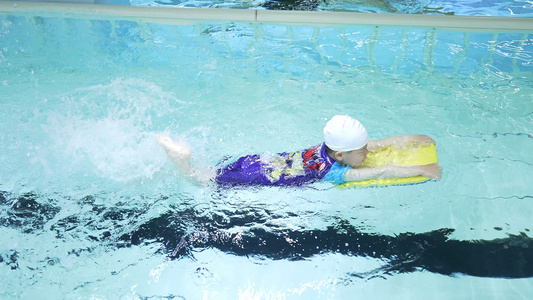 4K游泳课借助滑板练习游泳的小男孩视频