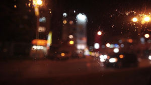 在你的城市中驾驶的抽象散焦灯夜间大雨滴在挡风玻璃上21秒视频