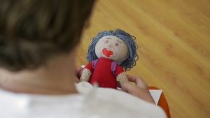 高级女人手里拿着针织娃娃关闭了拿着手工娃娃的年迈祖母21秒视频