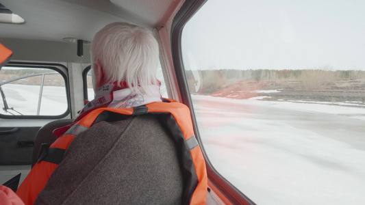 穿着安全夹克的高级妇女乘坐气垫船在结冰的河流上在冬季视频