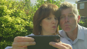 高加索夫妇在花园里的智能手机上自拍和做鬼脸19秒视频