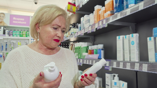 可爱的老女人笑着微笑在药店两件产品中做出选择视频