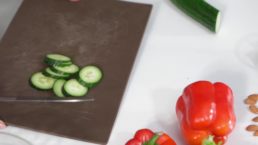 切菜板上的新鲜黄瓜片扔进一个普通的沙拉碗里为站在厨房视频
