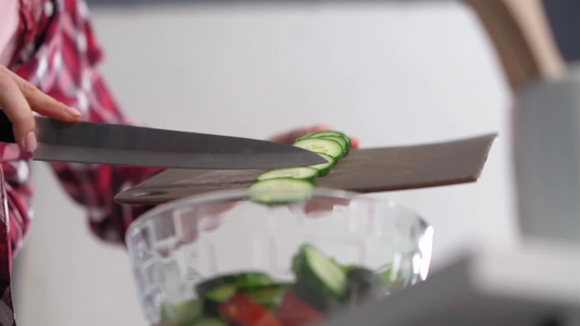 从砧板上扔进一个普通的沙拉碗正在厨房里做午餐的女人视频