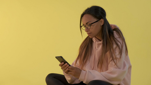 在智能手机上工作的眼镜里黑女人的特写视频