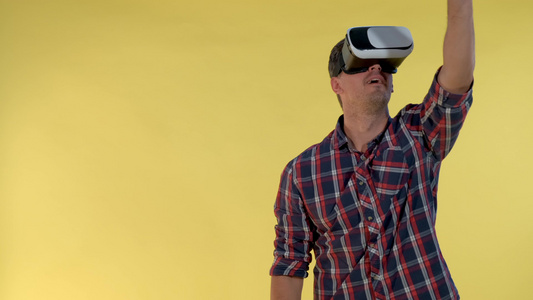 在黄色背景下站立时使用虚拟现实眼镜的深色头发男子视频