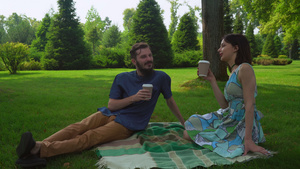 和女孩坐在公园里在地上说话和喝咖啡杯的男孩子18秒视频