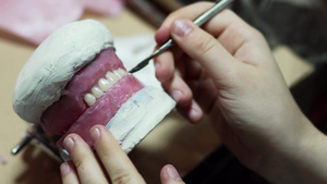 牙科技术员将多余的蜡从工作器上除去粉红色的牙蜡形式13秒视频