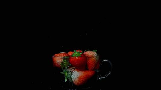 草莓落入玻璃杯中溅起水花的慢镜头视频